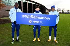 Players from a football team holding #weremember sign